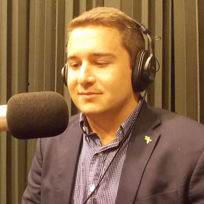 Kyle Baltuch sitting in WFSU's radio studio in front of the mic