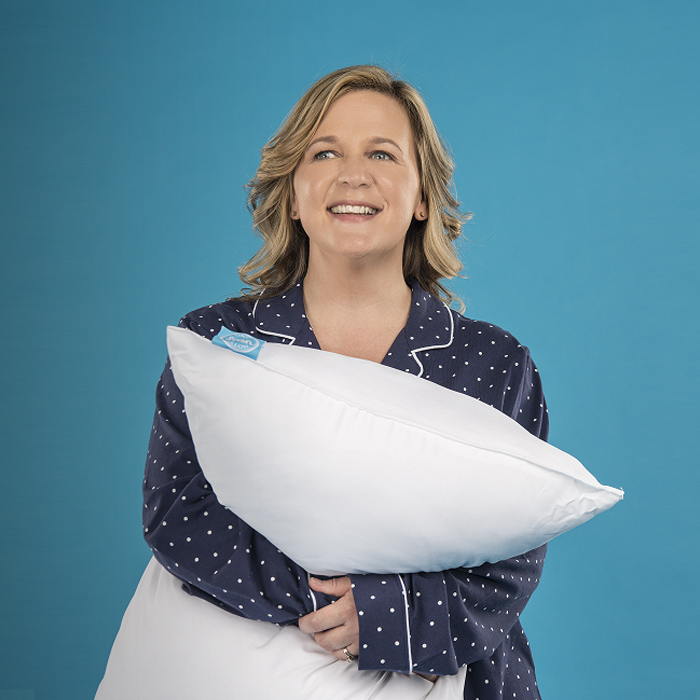 woman smiling and holding a pillow