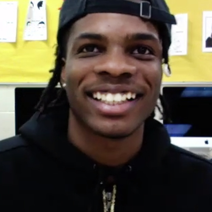 young man in a cap smiling, sitting in classroom