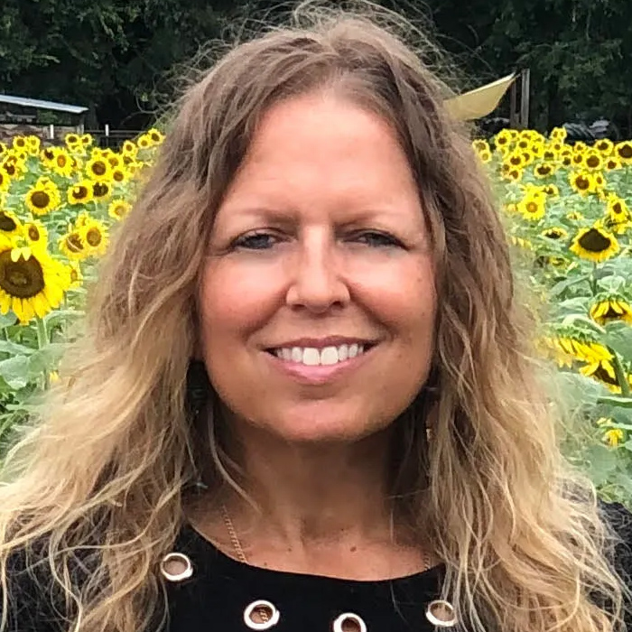 woman smiling surrounded by yellow flowers