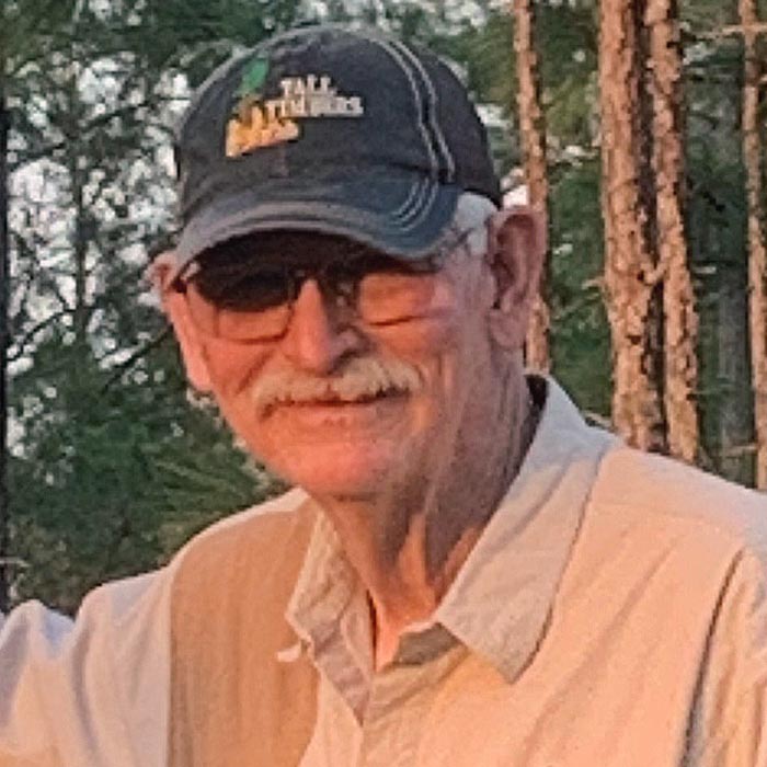 Man in a baseball cap in a forest.